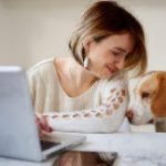 woman and brown dog by laptop