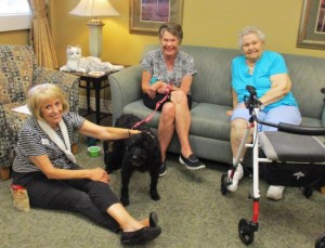 three senior women visiting with black dog