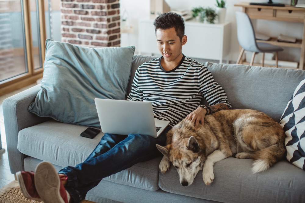 man and dog on couch with laptop