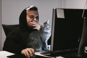 man and cat in front of computer