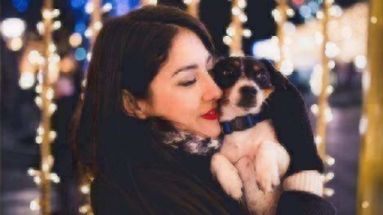 woman hugging dog in front of twinkle lights